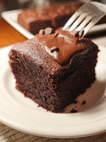 Slice of homemade chocolate cake with frosting being lifted