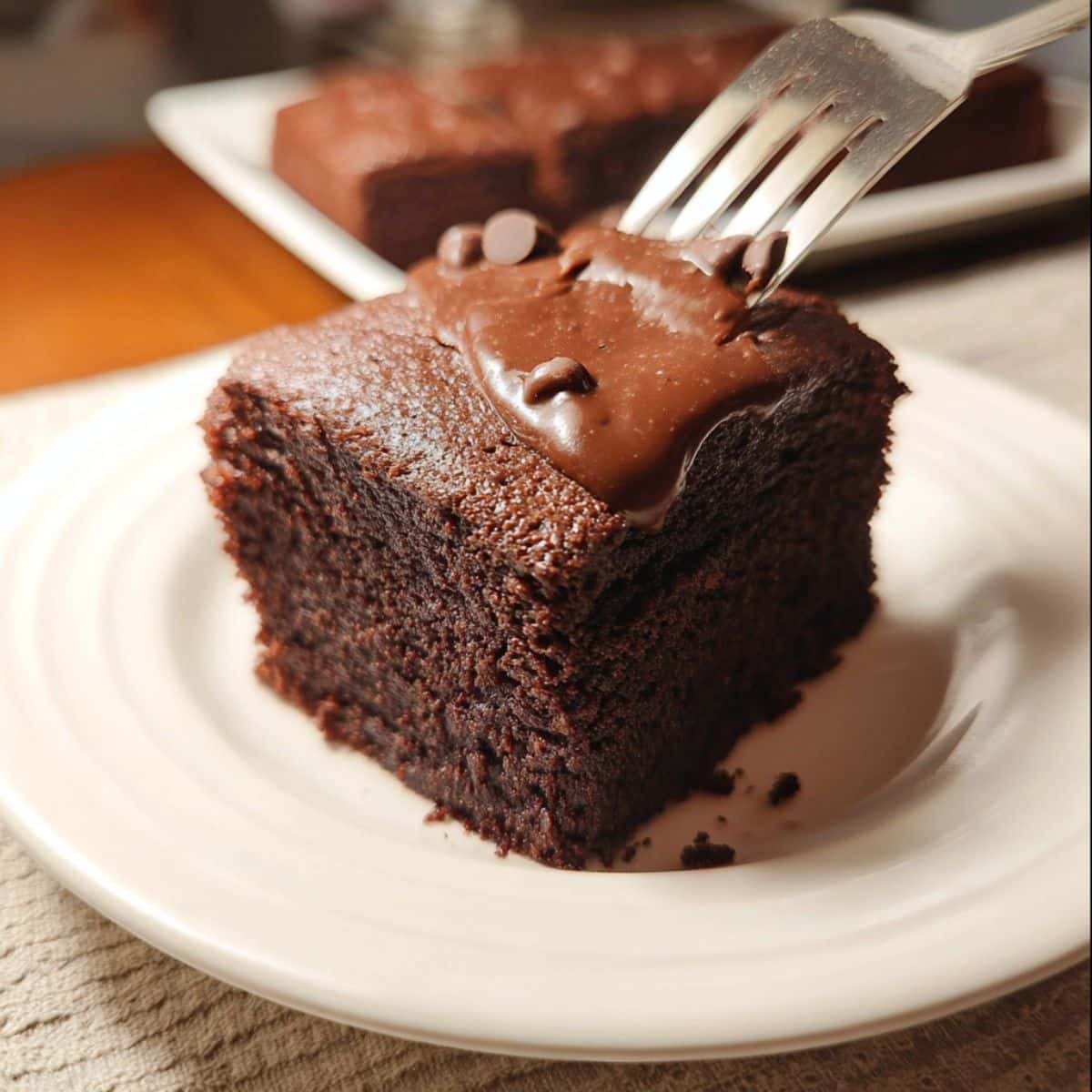 Slice of homemade chocolate cake with frosting being lifted	