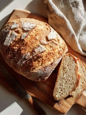 Freshly baked crusty Italian bread loaf sliced on a wooden board
