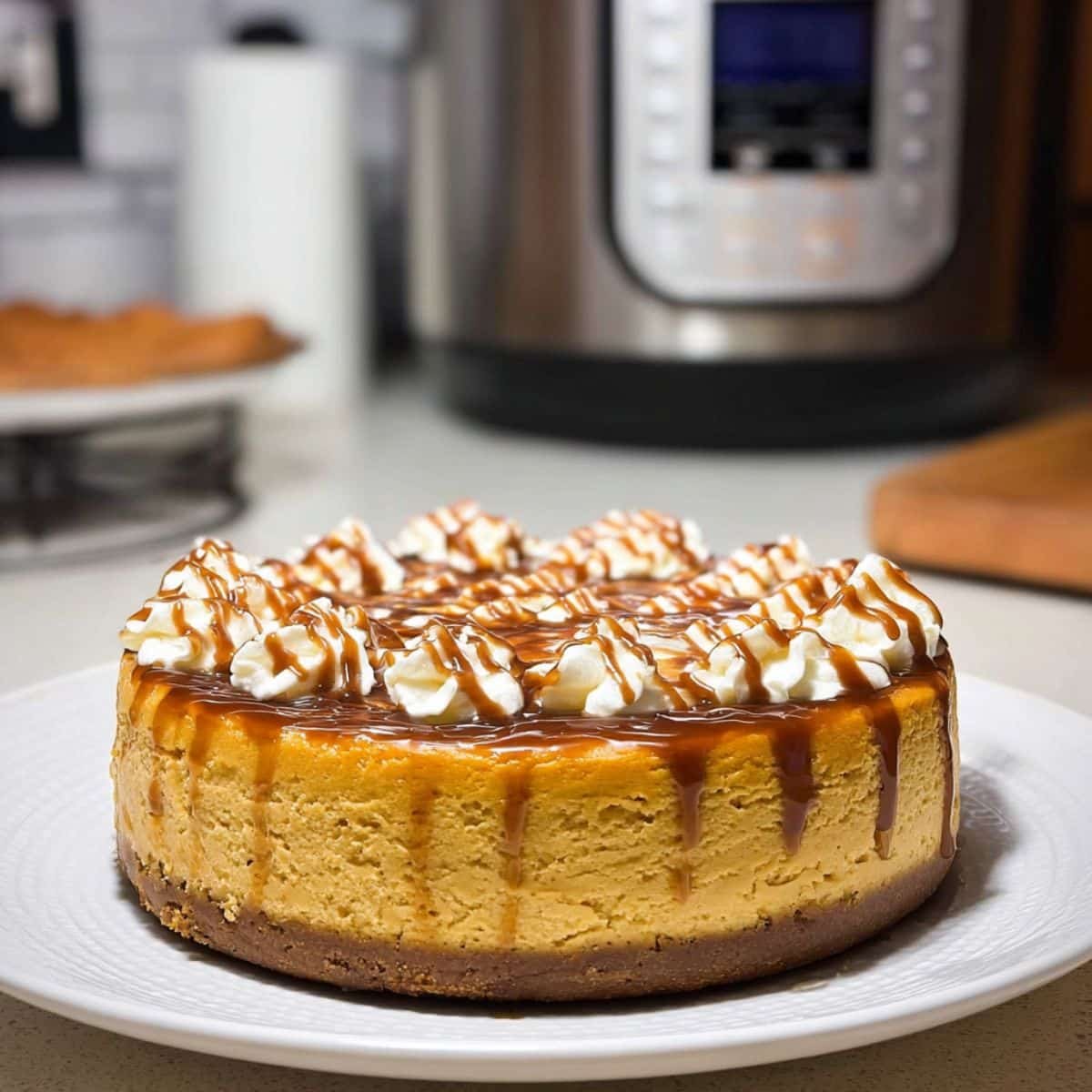 Homemade Instant Pot pumpkin cheesecake topped with caramel and chocolate drizzle on a white counter	