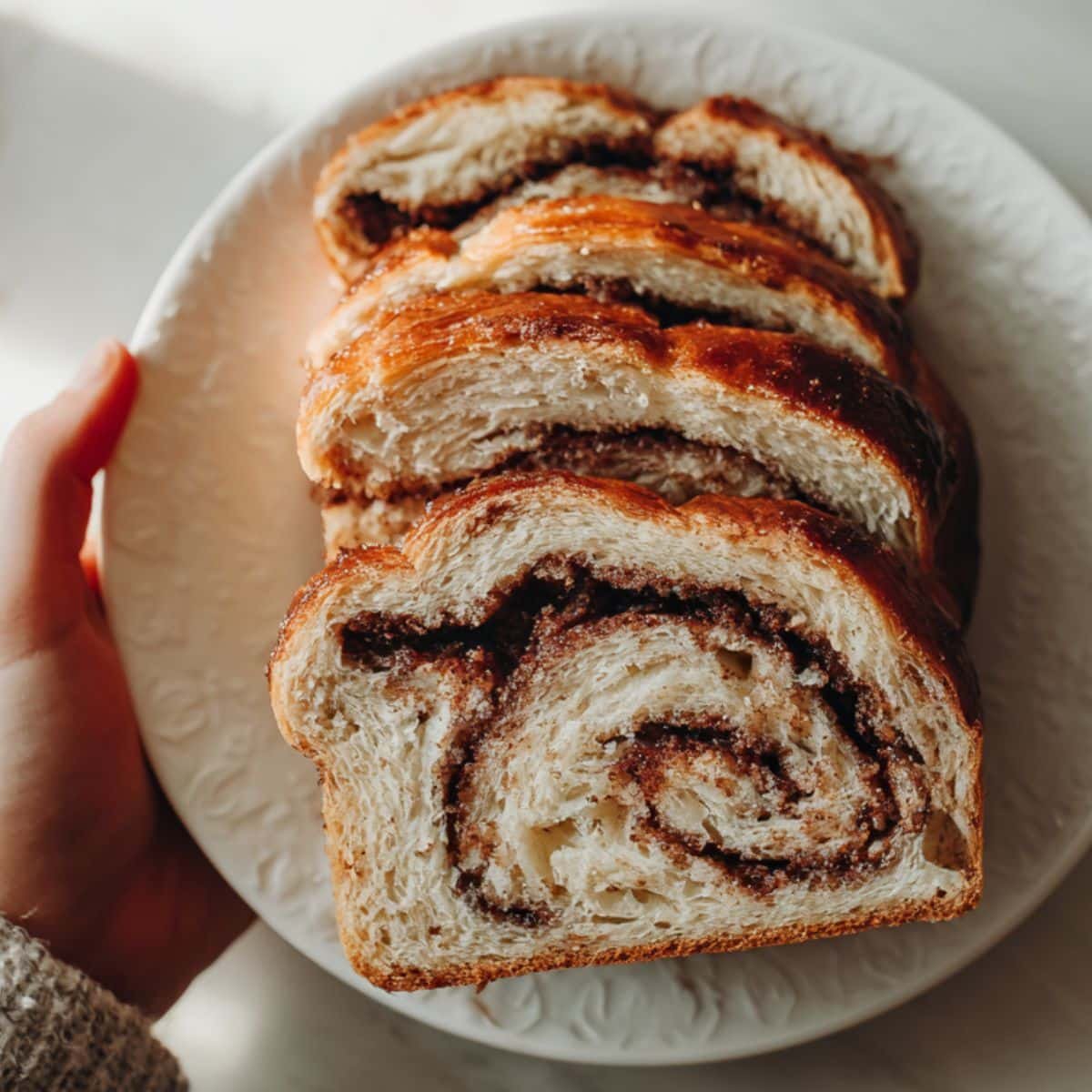 Spread cinnamon filling, roll dough tightly, place in loaf pan, and proof before baking
