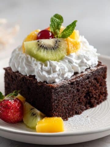A homemade chocolate brownie cake slice with whipped cream and fruit