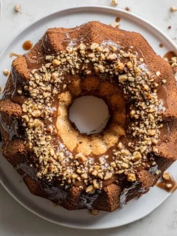 Homemade mocha chiffon cake with glossy coffee glaze and hazelnuts on a white plate