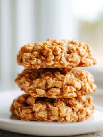 Close-up stack of soft, chewy no bake peanut butter oatmeal cookies on a white kitchen counter