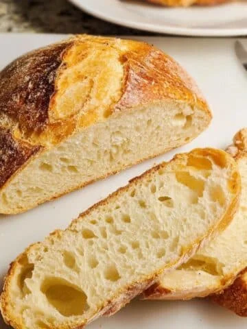 Rustic homemade Italian bread loaf and slices on white kitchen counter