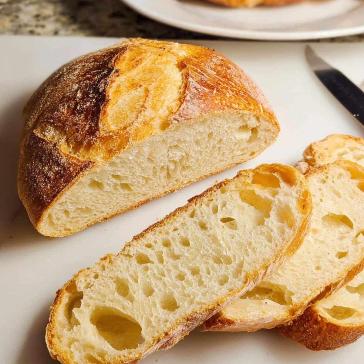 Rustic homemade Italian Bread Recipe loaf and slices on white kitchen counter	