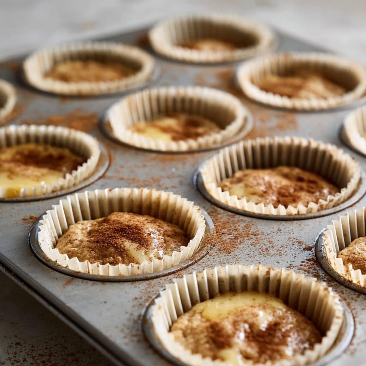 Muffin tin filled with batter and cinnamon sugar sprinkled on top	
