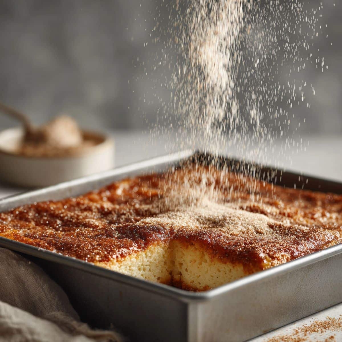 Sprinkling cinnamon sugar on warm cheesecake bars	