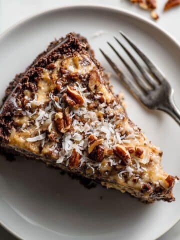 A slice of homemade German chocolate cheesecake with a rich chocolate base and coconut pecan topping.