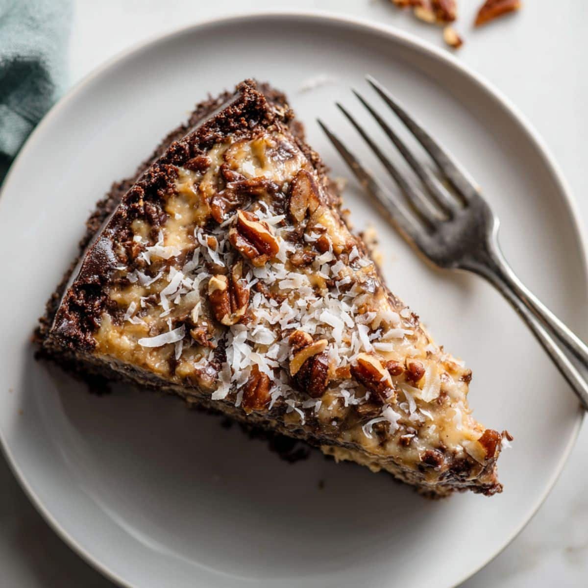 A slice of homemade German chocolate cheesecake with a rich chocolate base and coconut pecan topping.	
