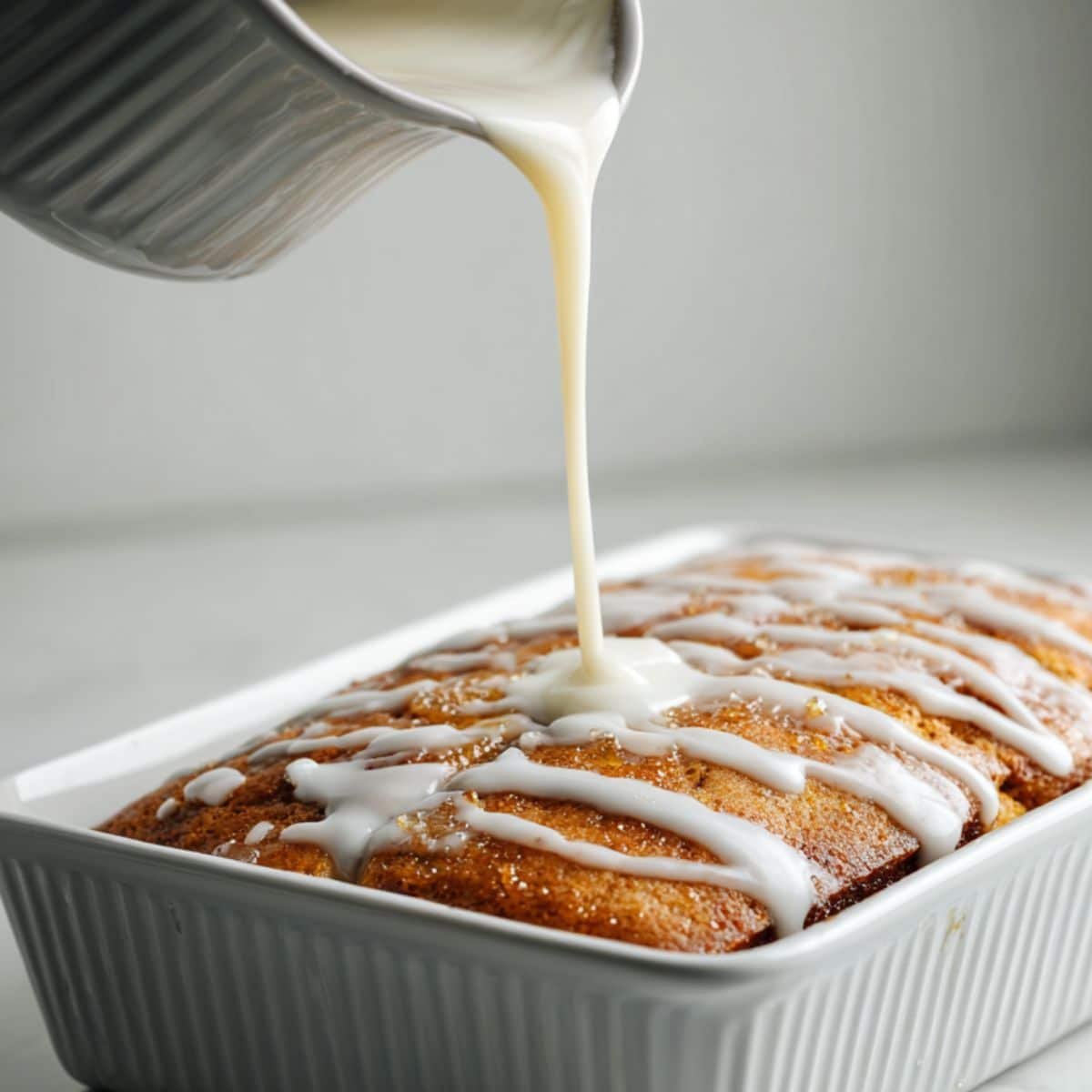 Pouring glaze over freshly baked honey bun cake	