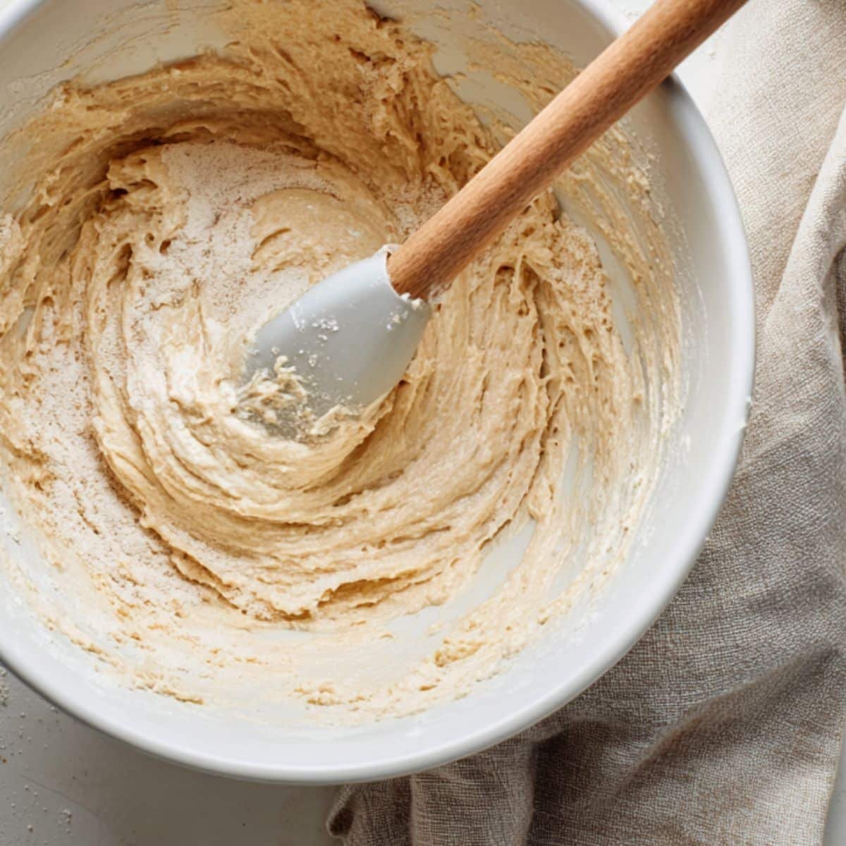 Gluten free funfetti cake batter being mixed with white spatula in a bowl	
