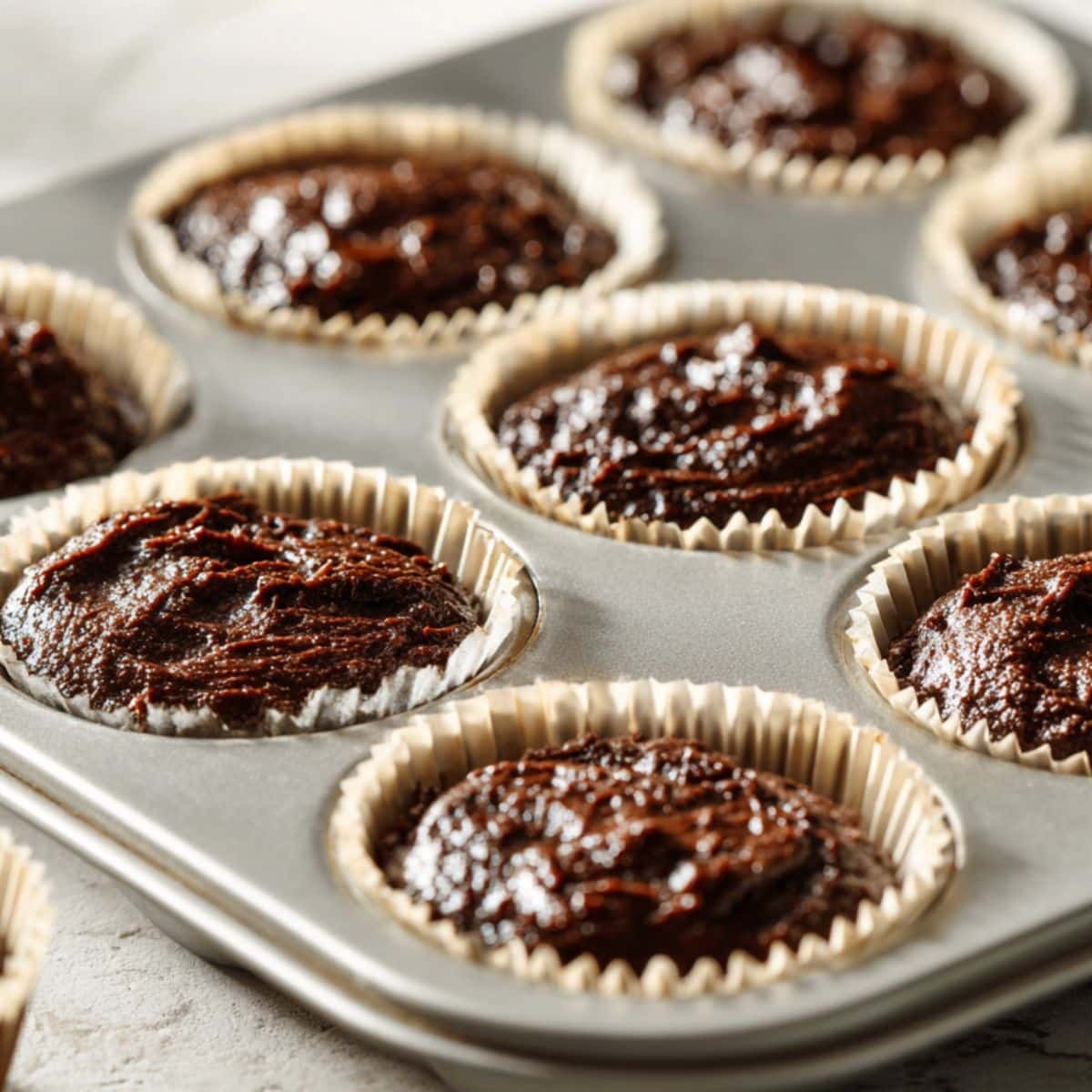Chocolate muffin batter in paper liners, ready to go in the oven	