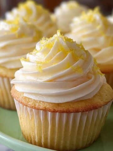 Fluffy lemon cupcake recipe with swirled buttercream and lemon zest on white plate