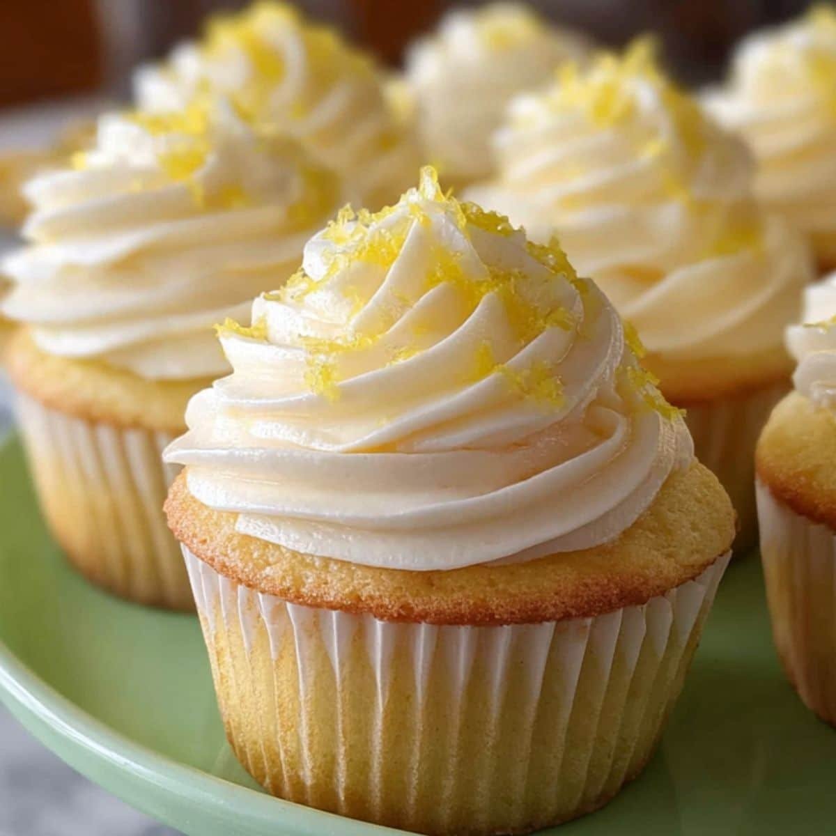 Fluffy lemon cupcake with swirled buttercream and lemon zest on white plate