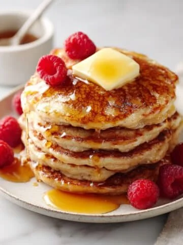 Stack of fluffy oat flour pancakes with maple syrup and butter melting on top
