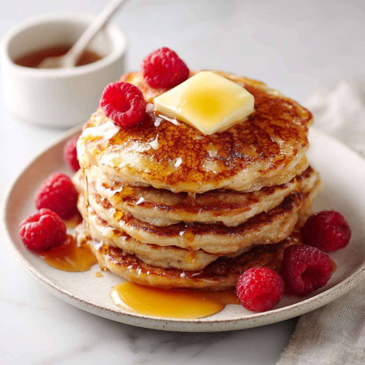 Stack of fluffy oat flour pancakes with maple syrup and butter melting on top	
