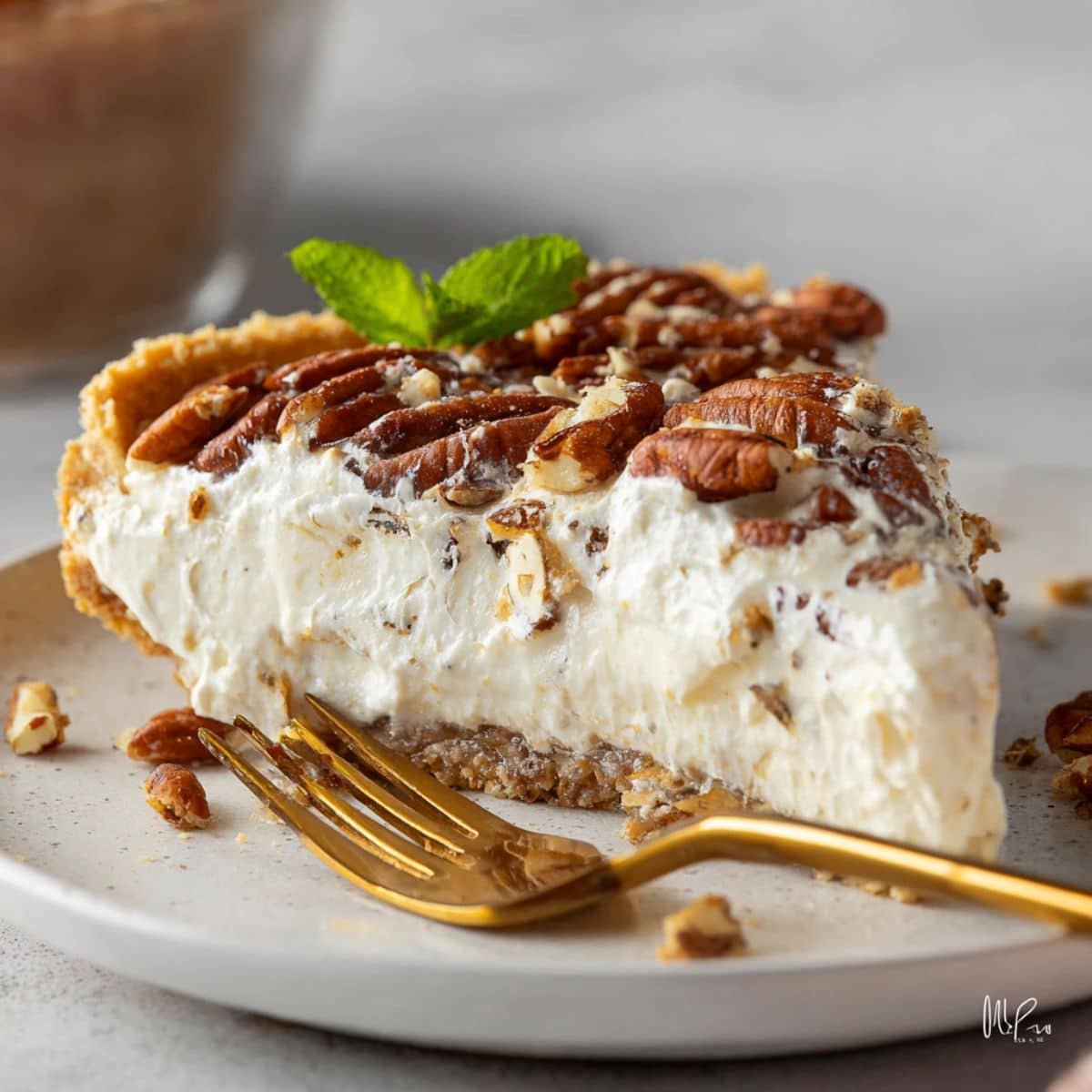 A generous slice of pecan cream pie on a plate with creamy filling and crunchy pecans on top