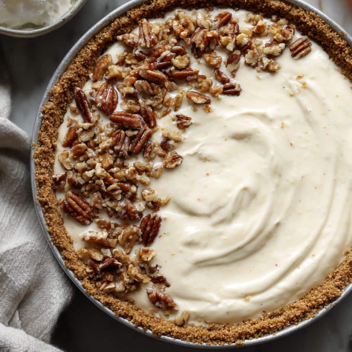 Cream filling spread inside crust and topped with pecans, ready to chill