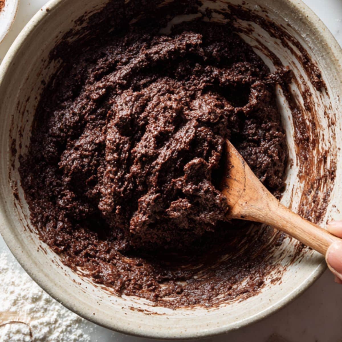 Mixing chocolate cookie dough in a bowl with ingredients around	