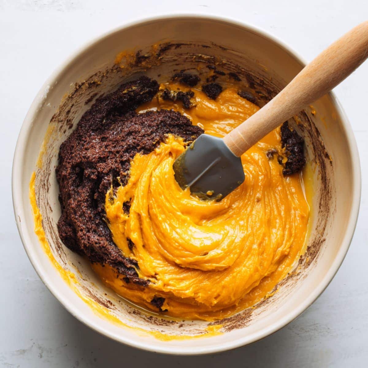 Mixing pumpkin and brownie batter in a bowl	