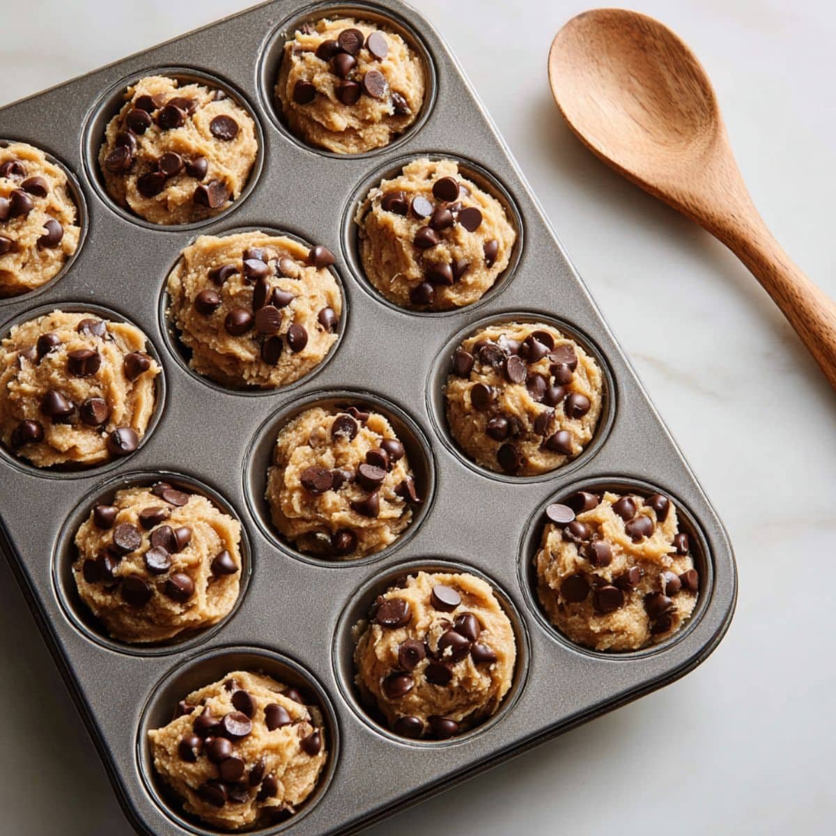 Pressing cookie dough into muffin pan cups for baking	