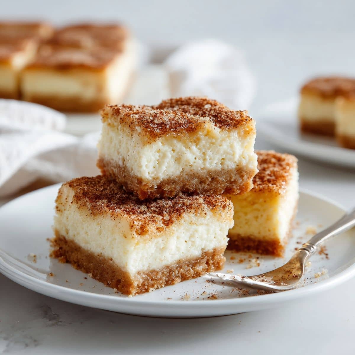 Close-up of sliced snickerdoodle cheesecake bars on white kitchen counter	