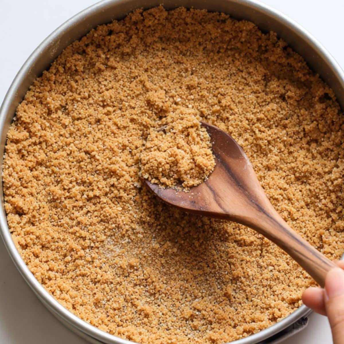 Pressing graham cracker crust into pan by hand	