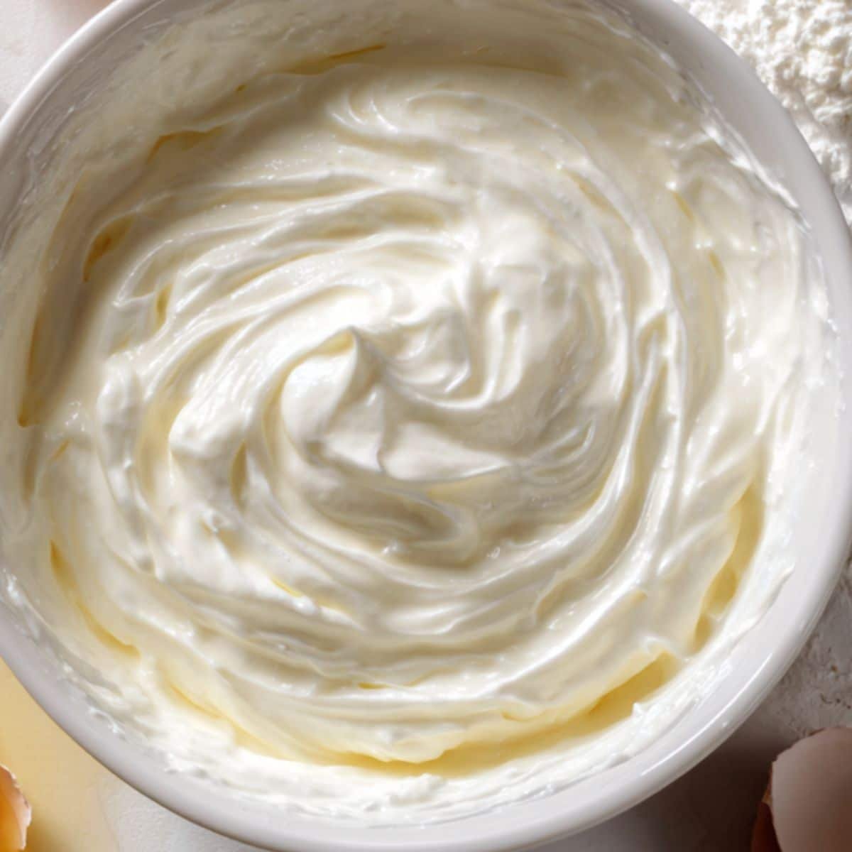 Egg whites being whipped with soft peaks forming in a white bowl	