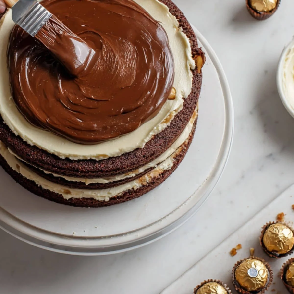 Layered cake being assembled and topped with ganache	
