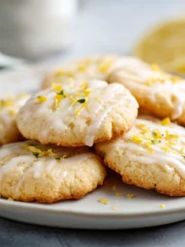 Plate of lemon shortbread cookies with lemon zest on a white table.