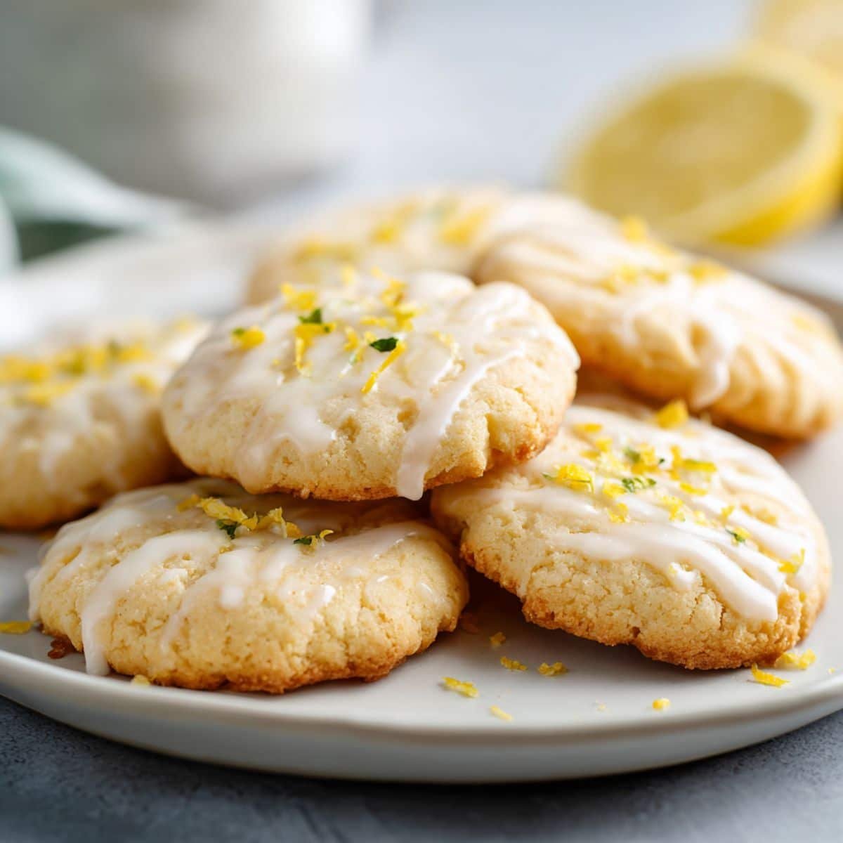 Plate of lemon shortbread cookies with lemon zest on a white table.
