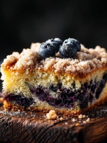 Homemade blueberry sour cream coffee cake with golden streusel topping on a white kitchen counter