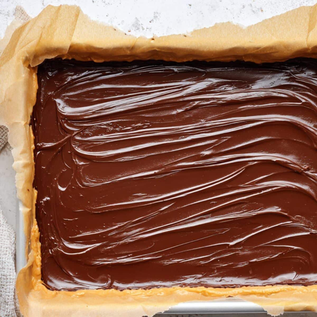 Chocolate layer being spread over peanut base	
