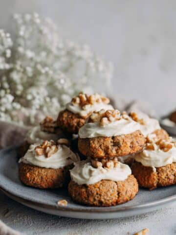Homemade carrot cake cookies with cream cheese frosting and walnuts on a plate