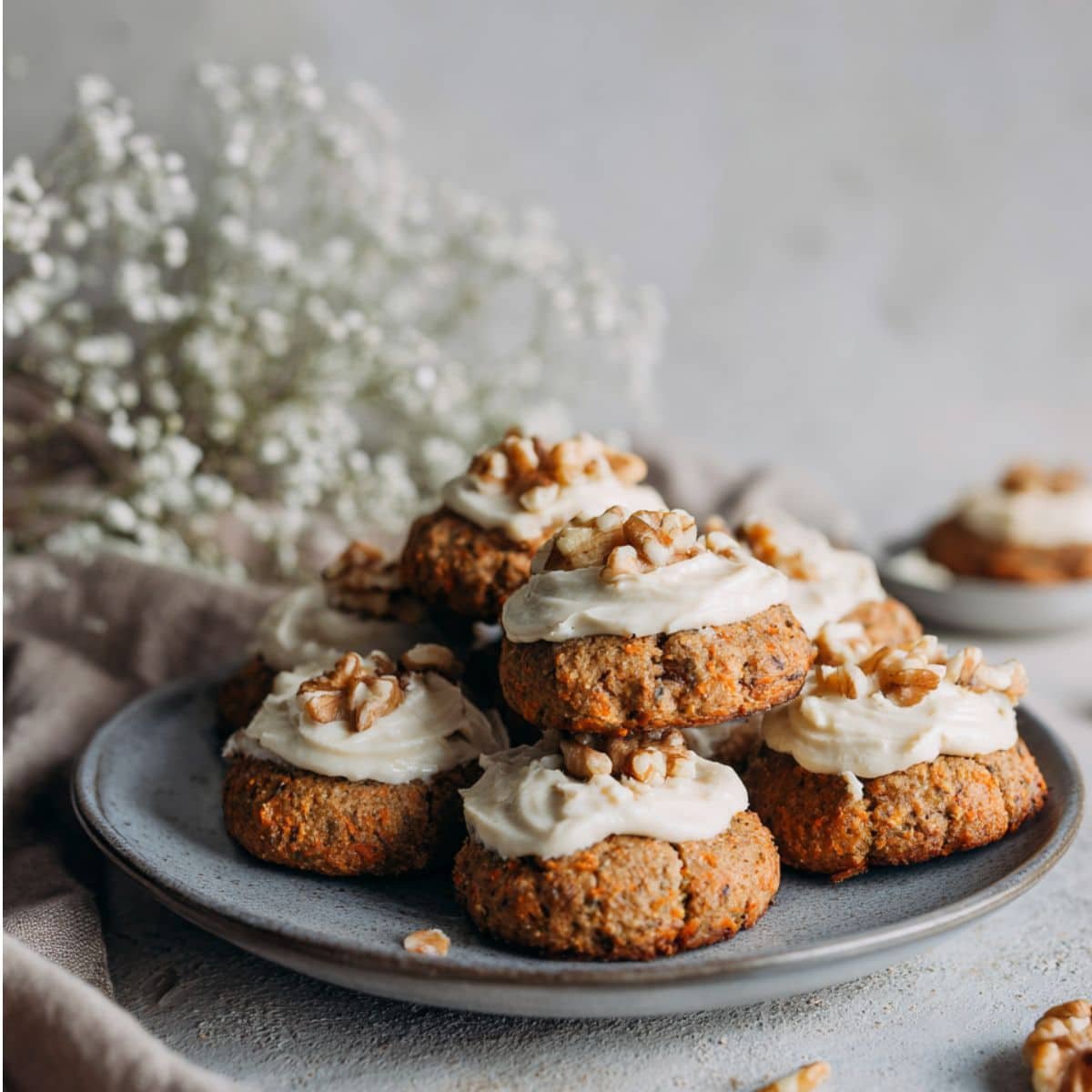 Homemade carrot cake cookies with cream cheese frosting and walnuts on a plate