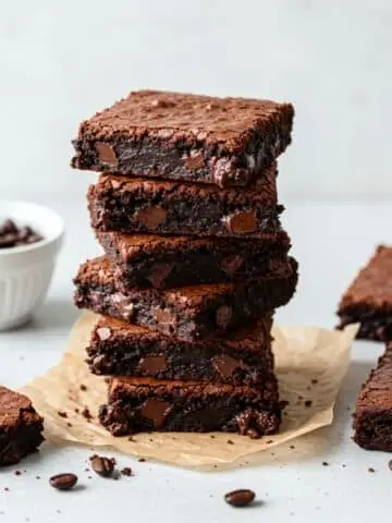 Fudgy espresso brownies stacked on parchment with melted chocolate swirls