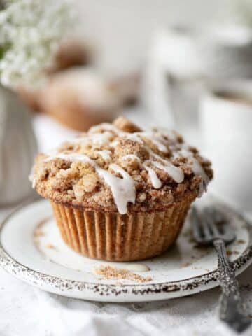 Close-up of a glazed cinnamon streusel coffee cake muffins on white ceramic plate