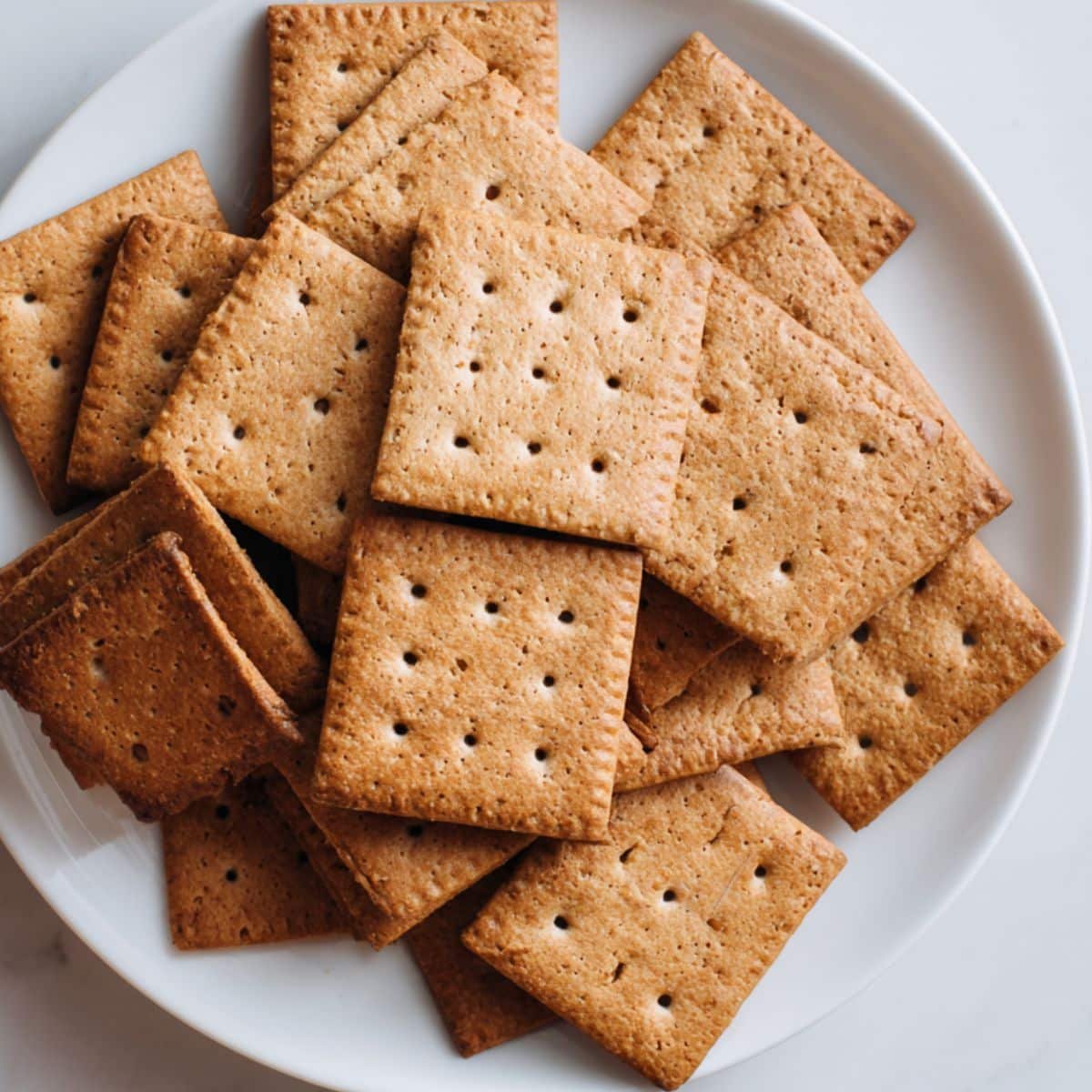 Homemade gluten free graham crackers stacked on white counter