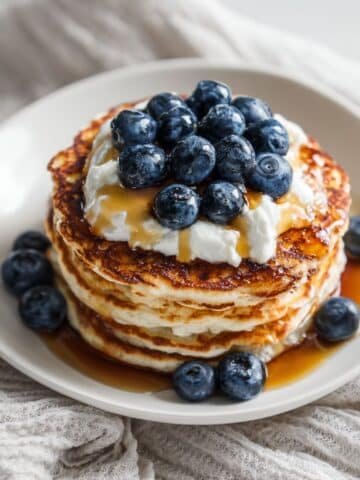 Stack of cottage cheese protein pancakes topped with blueberries and yogurt