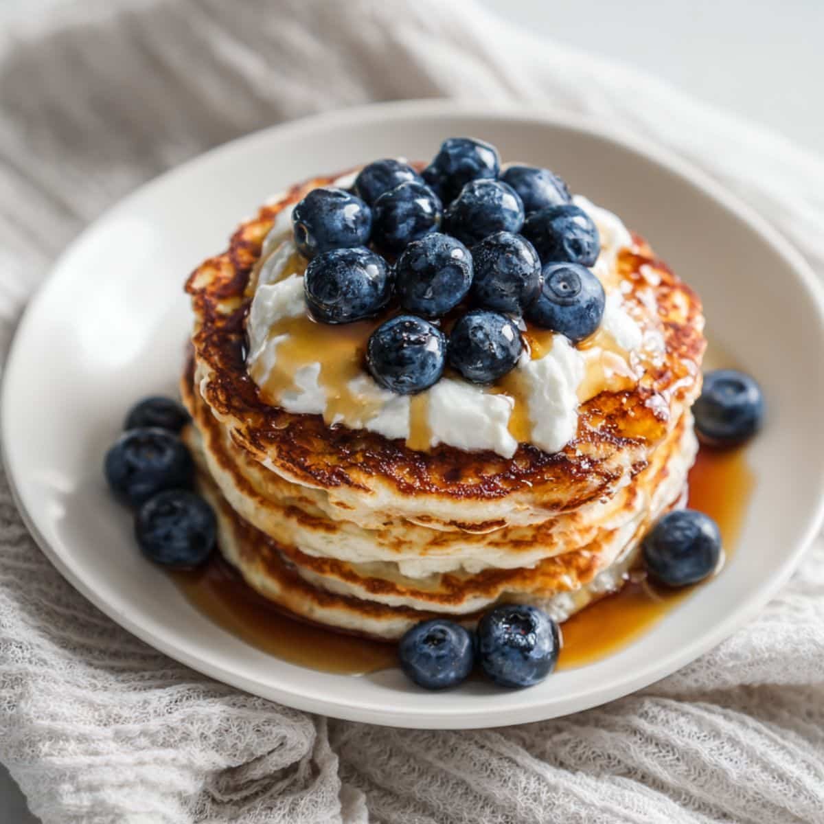 Stack of cottage cheese protein pancakes topped with blueberries and yogurt