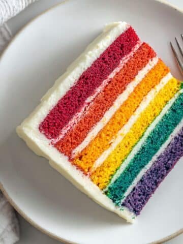 Homemade rainbow cake slice on a plate with colorful layers