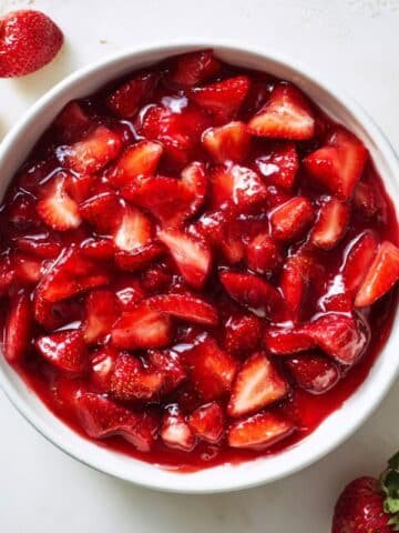 Fresh homemade strawberry pie filling in baked pie crust on white counter.