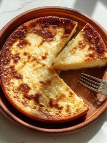 Golden brown baked 3 ingredient cassava cake served on a plate with a fork.