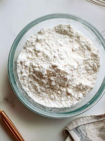 Homemade baking powder in a bowl with spoon on white counter