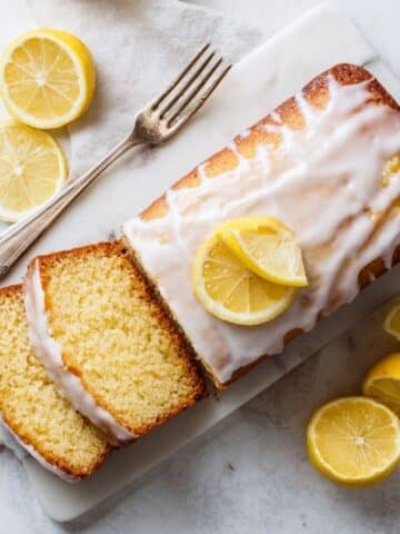 Moist lemon loaf cake slices with lemon glaze on a white plate in a bright kitchen