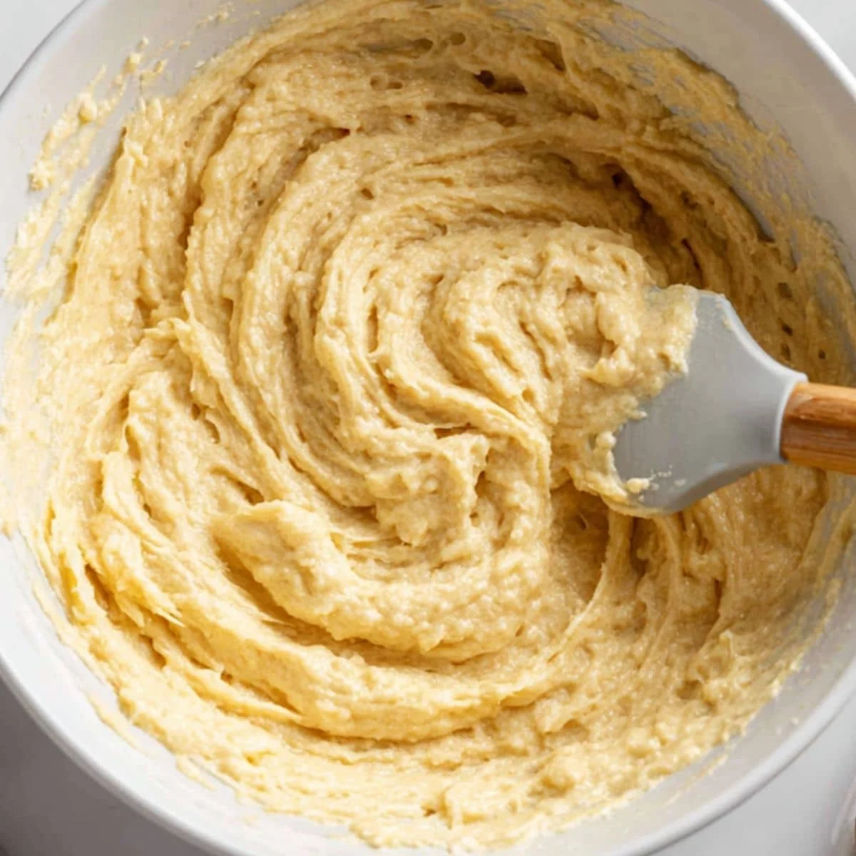 Creamy muffin batter in a mixing bowl with eggs, sour cream and vanilla	