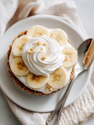 No bake mini banana cream pie with banana slices and whipped cream on graham crust