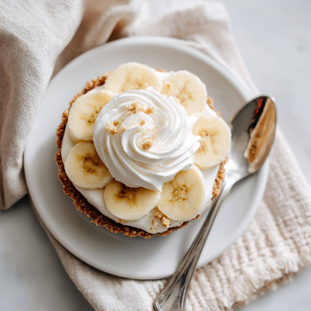 No bake mini banana cream pie with banana slices and whipped cream on graham crust	