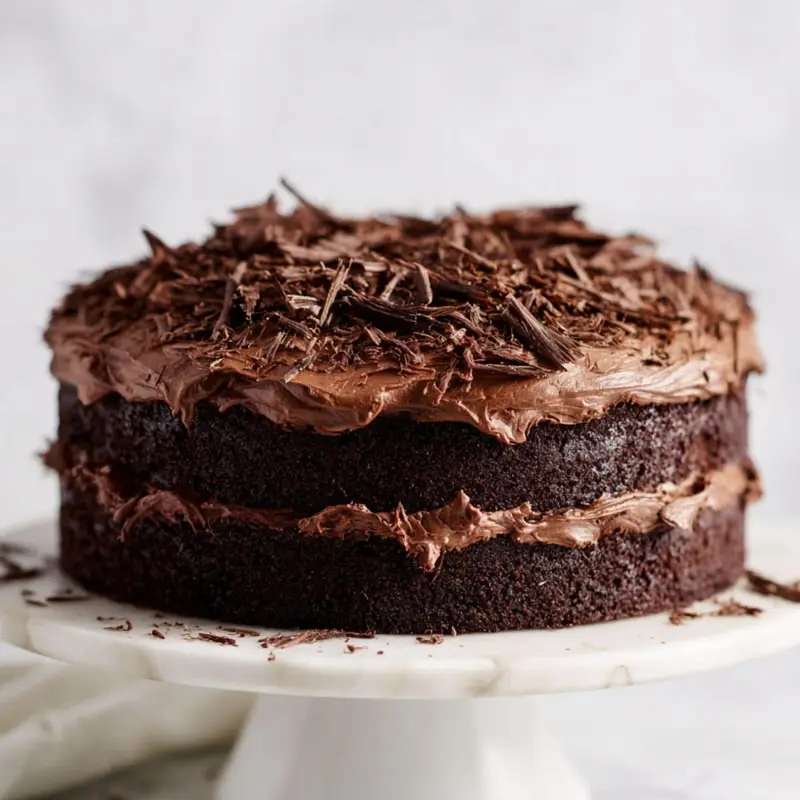 Finished Chocolate Hershey's Cake with creamy frosting and chocolate shavings on marble stand	